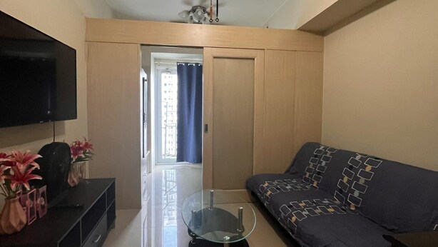 A living room with a ceiling fan, a TV, a glass coffee table, a sofa, and a door leading to a balcony. - Property near to Trident,Ayala,BGC and Airport and Supermarket & restaurant (Makati)