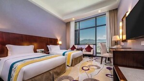 A hotel room with two beds, a desk, a chair, a TV, and a large window with a mountain view. - Fuzhou Rongtong Meifeng Hotel (Fuzhou)