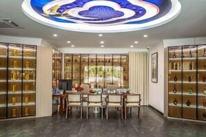 A room with a dining table, chairs, a TV, and shelves with decorative items. - Fuzhou Rongtong Meifeng Hotel (Fuzhou)