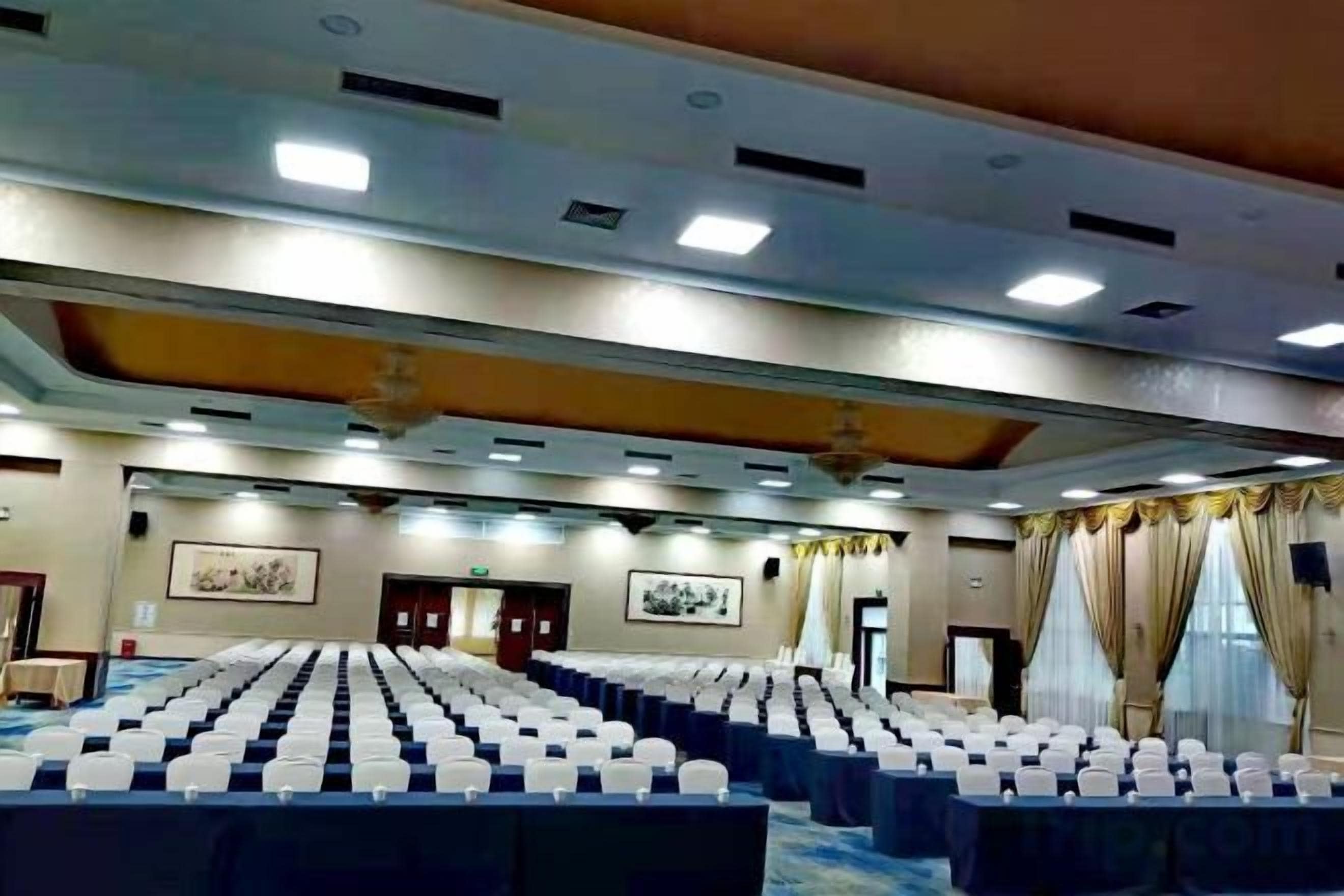 Ein Konferenzraum mit Reihen von Stühlen, einer Bühne und einer Decke mit Einbuchtungslichtern.