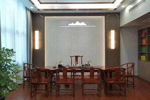 Uma sala de jantar com uma mesa redonda e cadeiras, uma planta em vaso e uma parede com luminária decorativa.