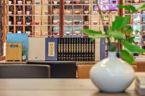 A table with a vase and books, a bookshelf with various items, and a wooden cabinet. - Fuzhou Rongtong Meifeng Hotel (Fuzhou)