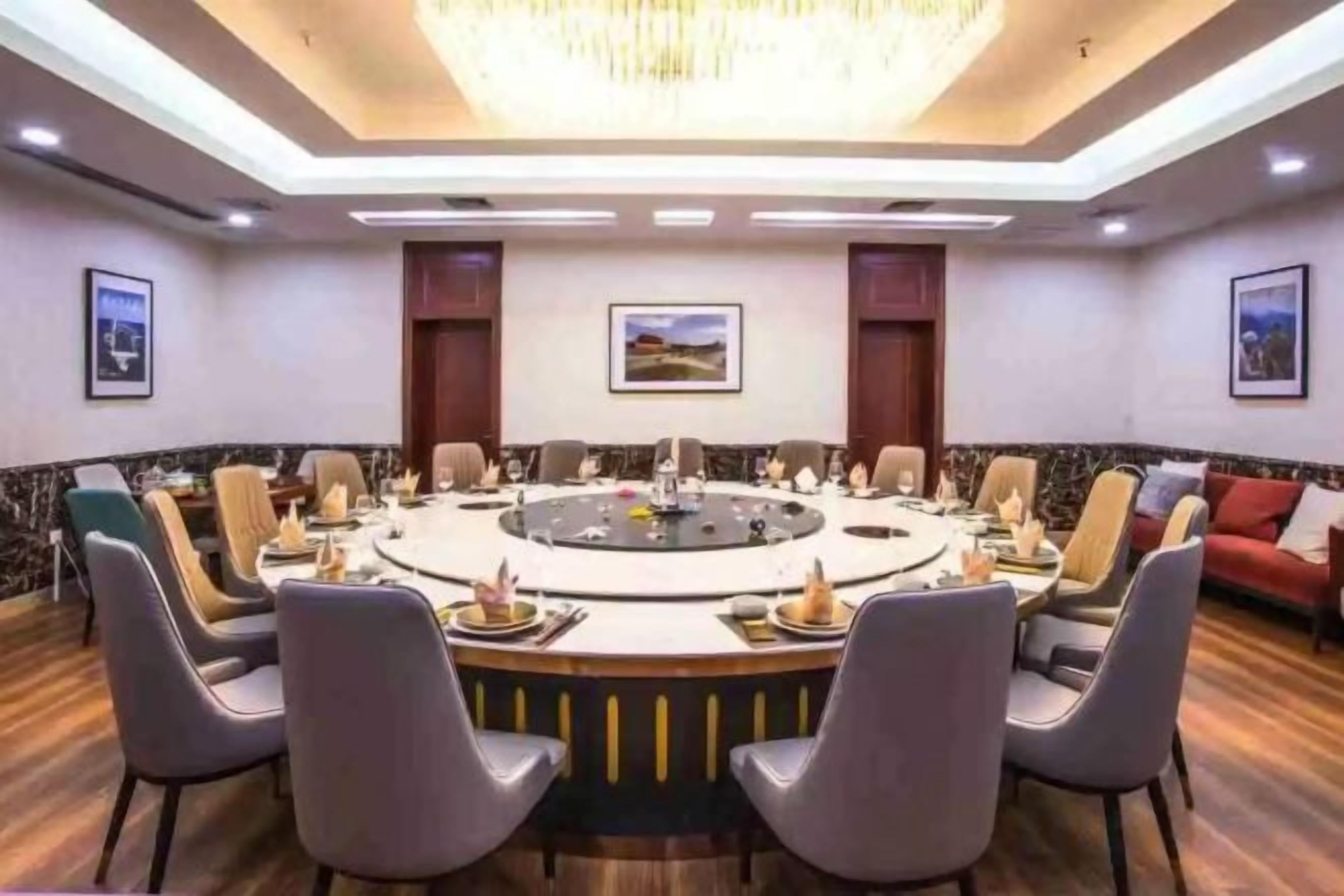 A conference room with a round table, chairs, and a chandelier.