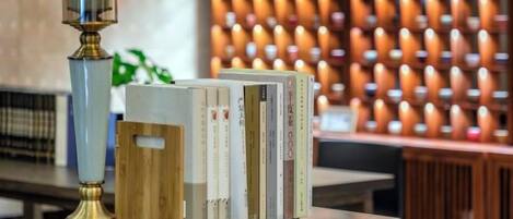 A stack of books on a wooden surface with a tall, slender lamp beside them.