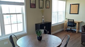 Ein Essbereich mit einem runden Tisch, vier Stühlen, einer Blumenvase und einer Pinnwand.