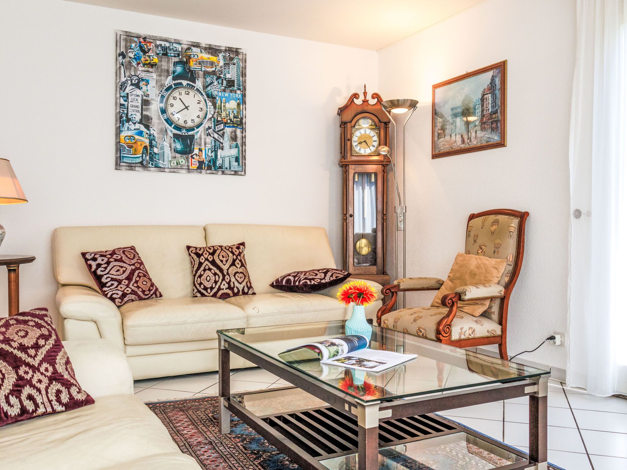 Un salon comprenant un canapé, un fauteuil, une table basse, une horloge et des œuvres d’art.