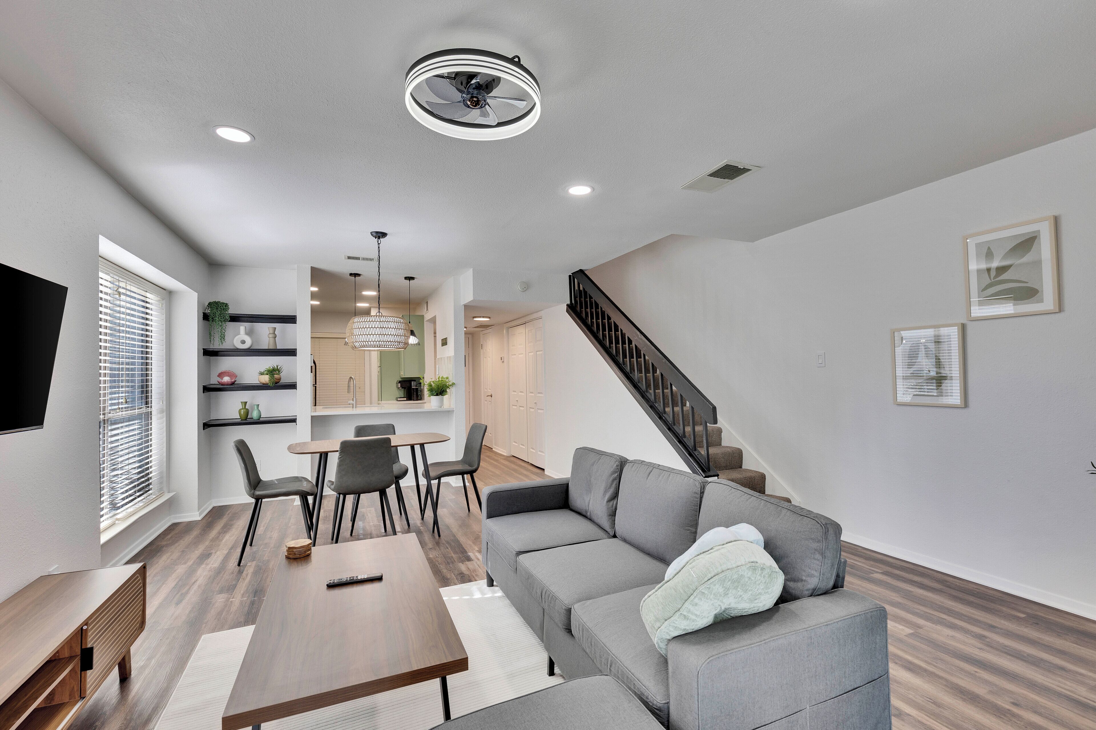 A modern living room with a gray sofa, a wooden coffee table, and a dining area with a small table and chairs.