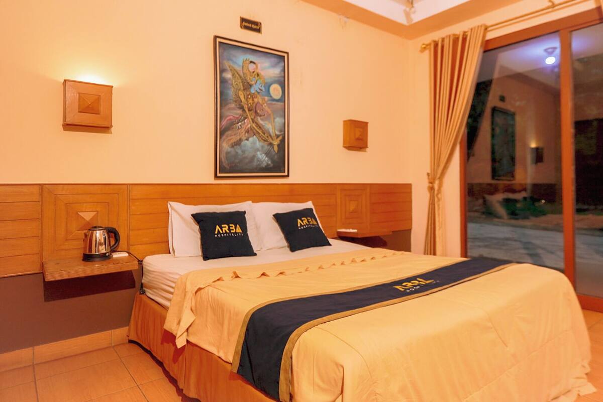 Hotelkamer met een bed, nachtkastje, schilderij en uitzicht.
