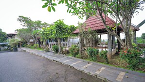 A covered outdoor seating area with a red roof, surrounded by greenery and trees. - Lembah Gunung Kujang by ARBA (Cijambe)