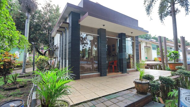 A modern hotel with a covered entrance, outdoor seating, and lush greenery. - Lembah Gunung Kujang by ARBA (Cijambe)