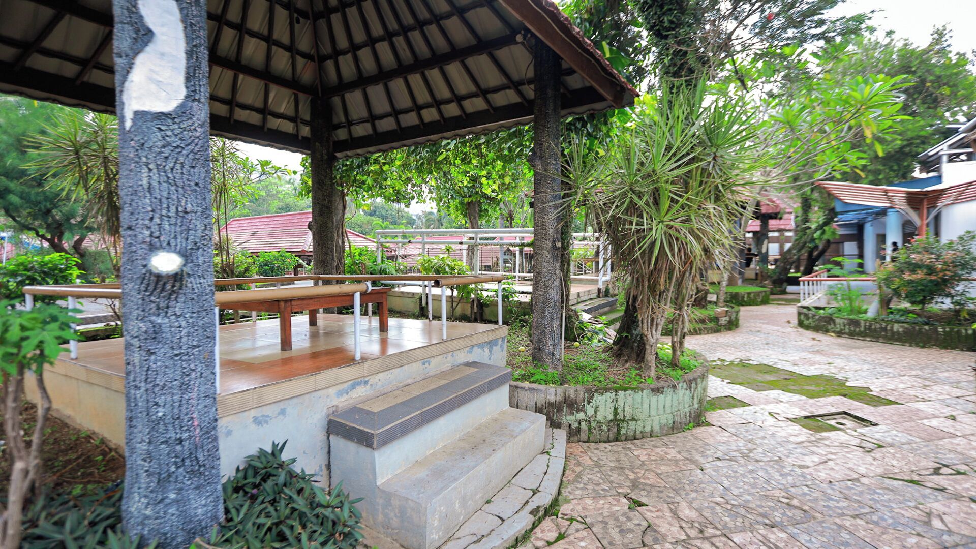 A covered outdoor area with a wooden bench and steps leading up to a platform.