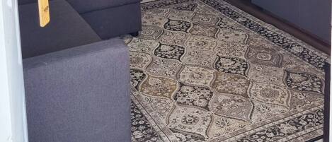 A living room with a sofa, a TV, a cabinet, and a patterned rug.