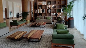 Eine großzügige Lobby mit einer Couch, zwei Holztischen und einem Bücherregal voller Dekoration.