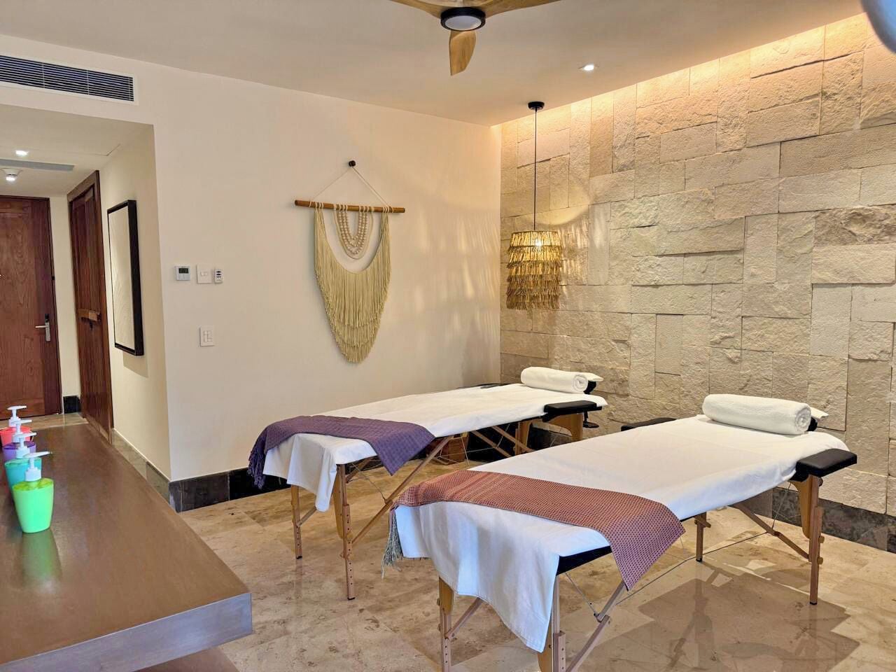 Un cuarto de spa con dos camillas de masaje, un mostrador de recepción y una pared de piedra.
