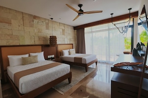 Habitación de hotel con dos camas, un escritorio, un ventilador de techo y un ventanal con vistas a zonas verdes.