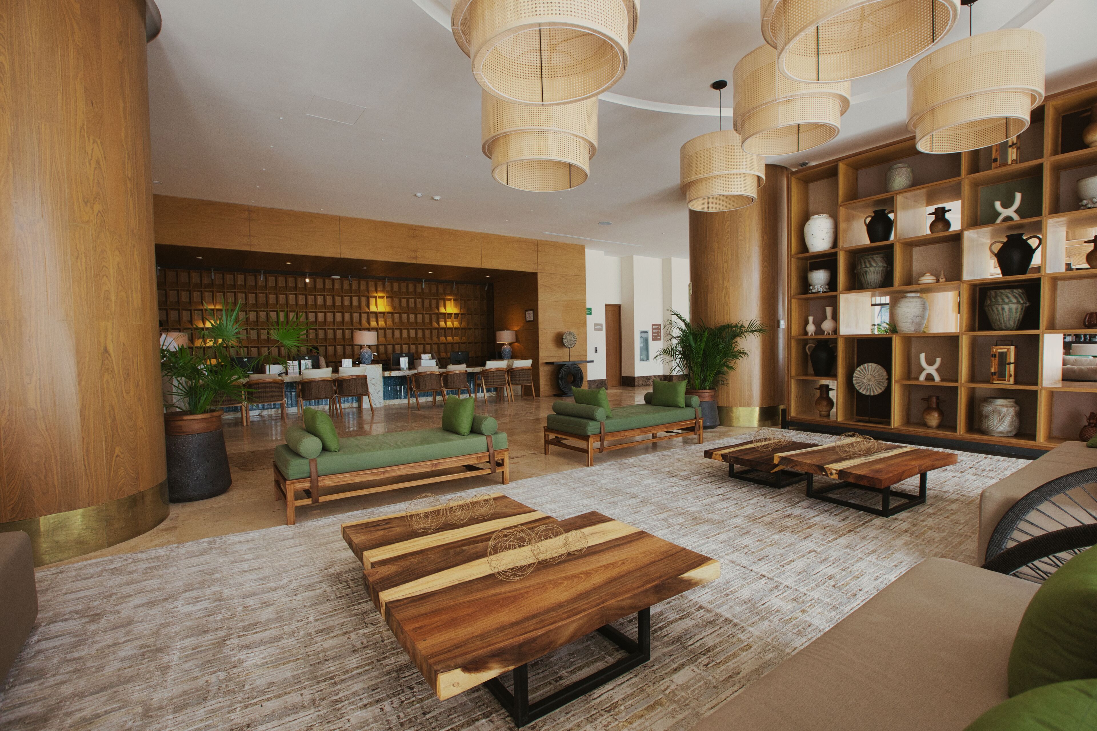 Eine geräumige Lobby mit Holzmöbeln, einem Empfangstresen und einem dekorativen Regal mit Keramik.
