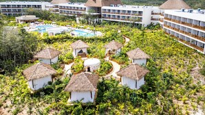 Ein Resort mit mehreren Gebäuden, einem zentralen Pool und strohgedeckten Hütten.