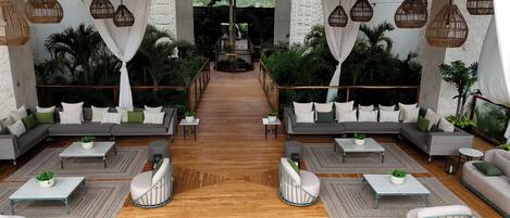 A spacious indoor area with a wooden floor, two sofas with cushions, a coffee table, and hanging wicker lamps.