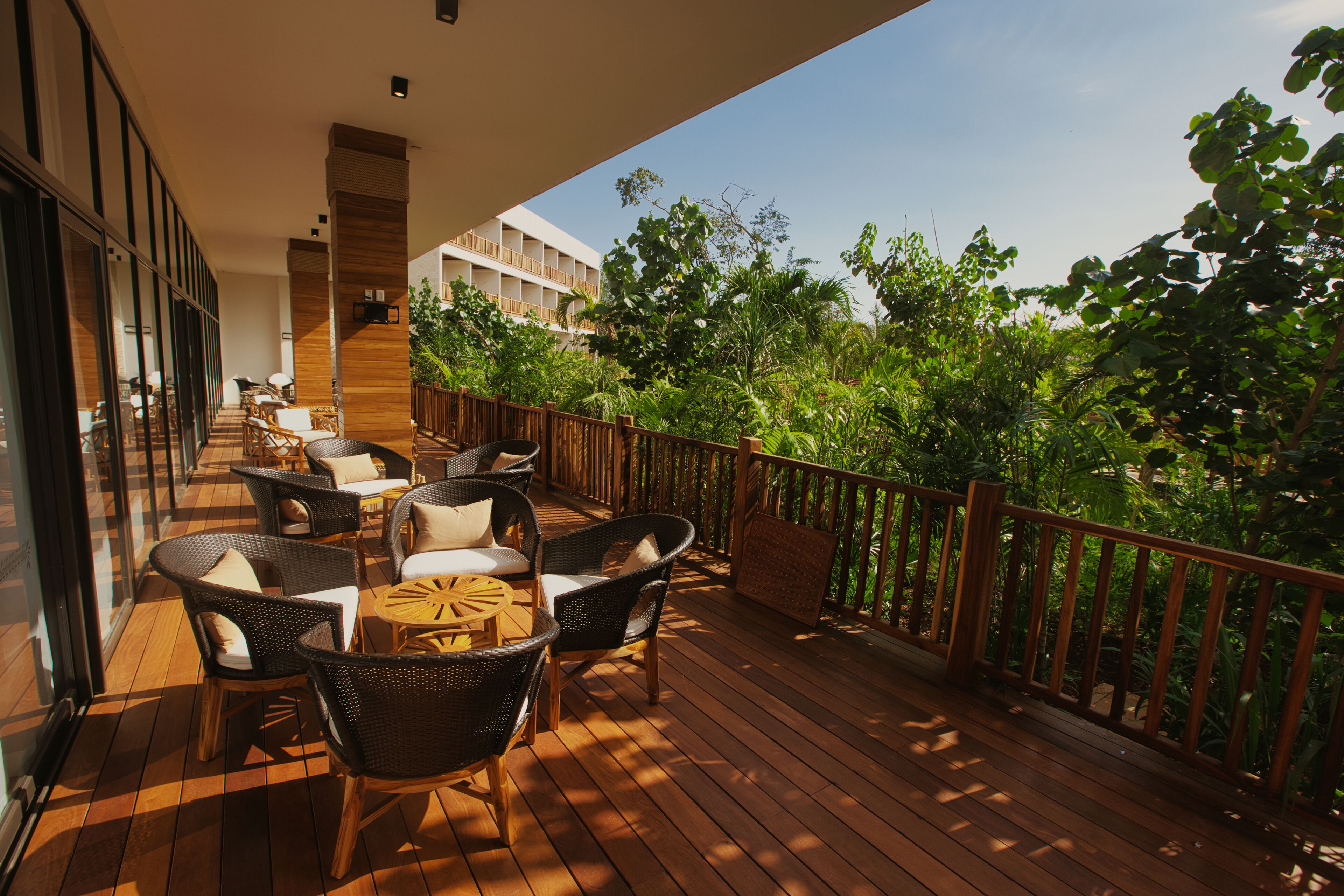 A wooden deck with wicker furniture and a view of lush greenery.