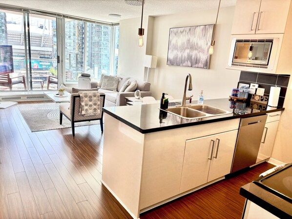A modern kitchen with a central island, a built-in oven, and a large window overlooking a cityscape.