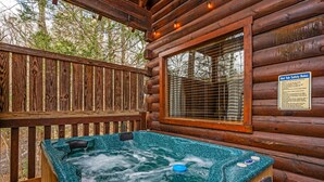 A hot tub in a wooden cabin with a wooden deck and a window. - Cozy Cabin Retreat: Hot Tub, Fire Pit & Game Room – Perfect Getaway! (Sevierville)