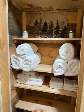 Ein Holzregal mit ordentlich gefalteten weißen Handtüchern.