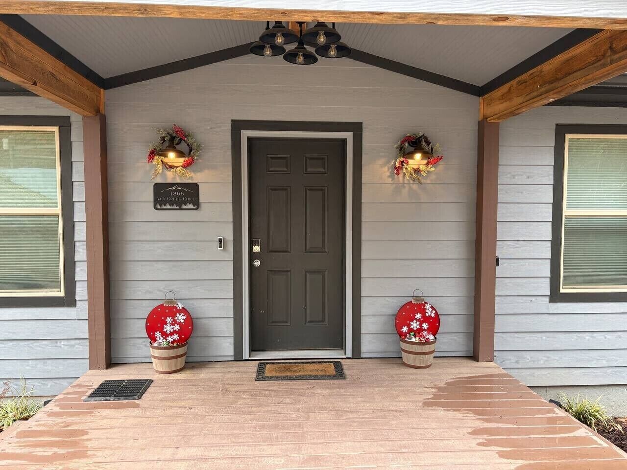 A house with a dark front door, two wreaths on either side, and a sign above the door.