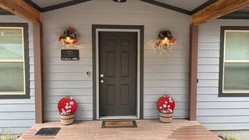 A house with a dark front door, two wreaths on either side, and a sign above the door.