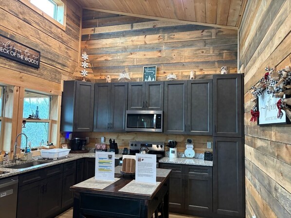 A rustic kitchen with wooden walls, a stainless steel microwave, and a coffee maker.