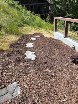 A pathway with stepping stones leading to a building with a deck.