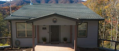 A single-story building with a porch, a chimney, and a view of a mountainous landscape.
