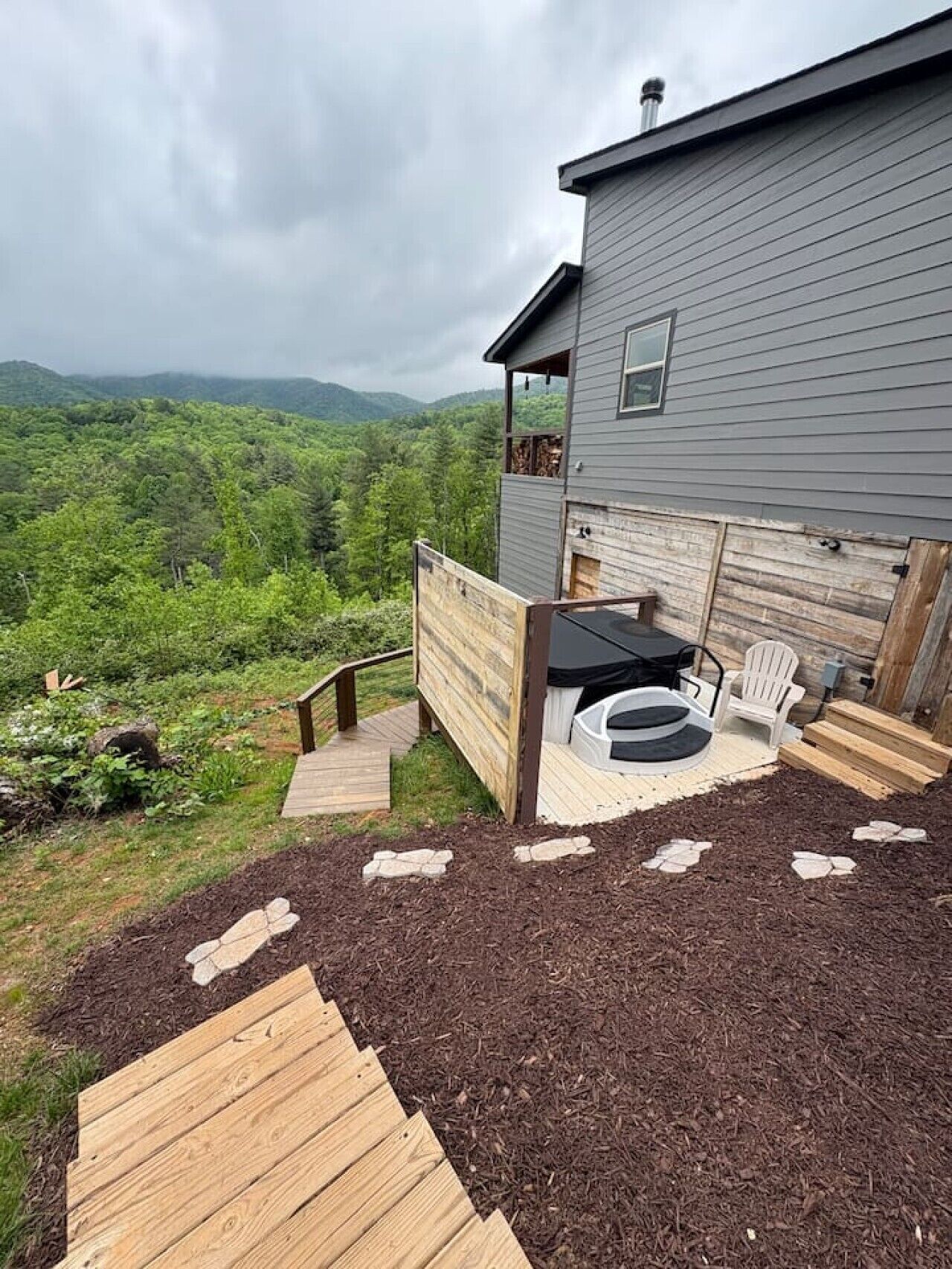 A wooden deck with a black outdoor seating area, a small table, and a chair.