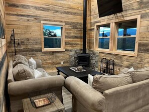 Ein gemütliches Interieur mit einer Sofagarnitur, einem Kamin und Fenstern mit Ausblick.