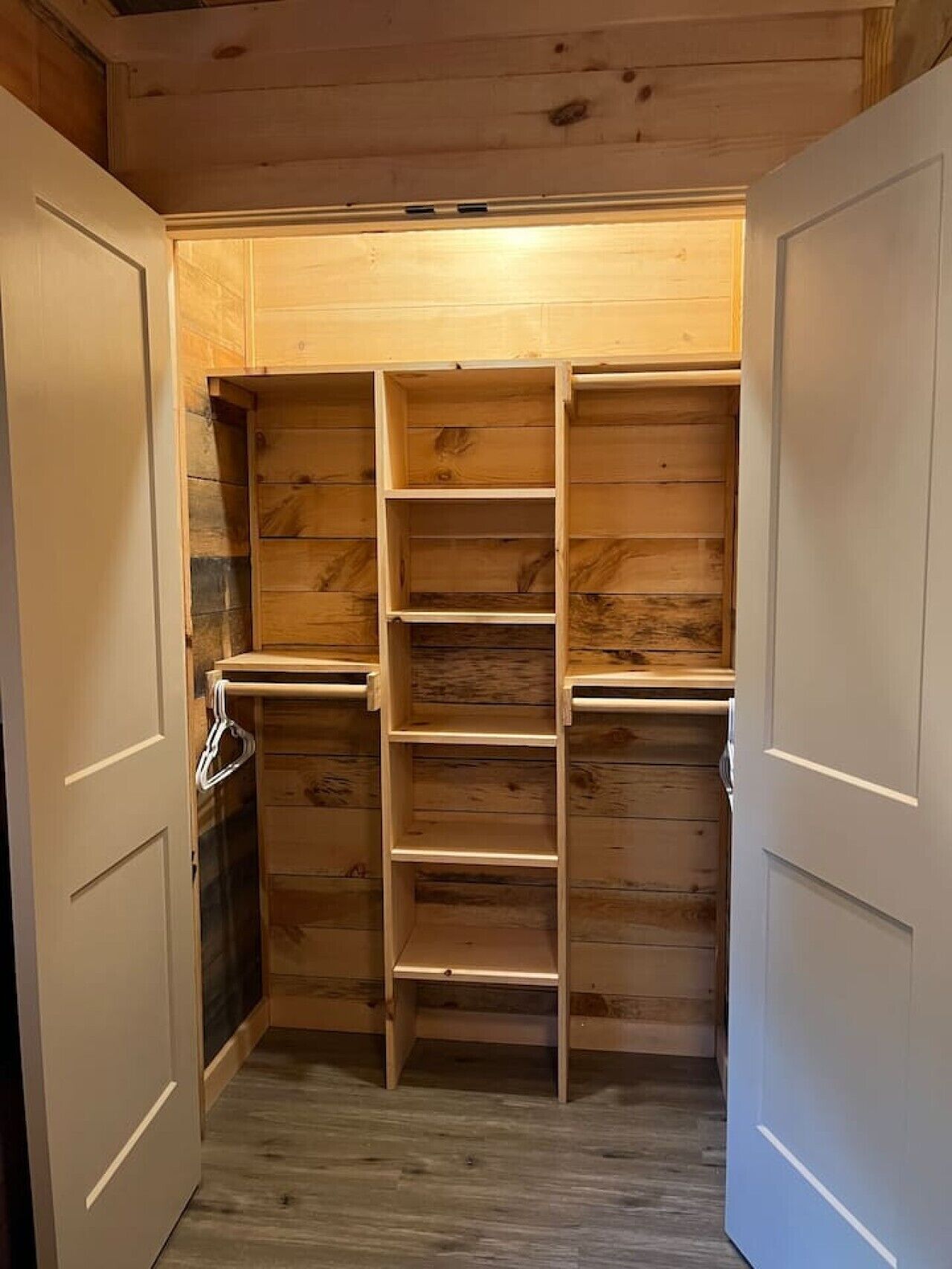 A wooden closet with multiple shelves and hanging space.