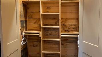 A wooden closet with multiple shelves and hanging space.
