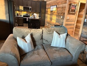 Ein Wohnzimmer mit einem beigefarbenen Sofa, zwei gestreiften Kissen und einer Holzwand.