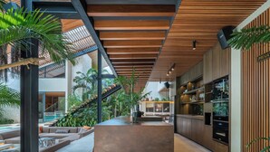 A modern kitchen with built-in appliances, a central island, and a dining area with a pool view. - Villa Baratega (Kerobokan)