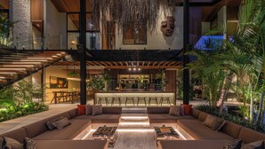 A modern interior with a central seating area, a bar, and a staircase. - Villa Baratega (Kerobokan)