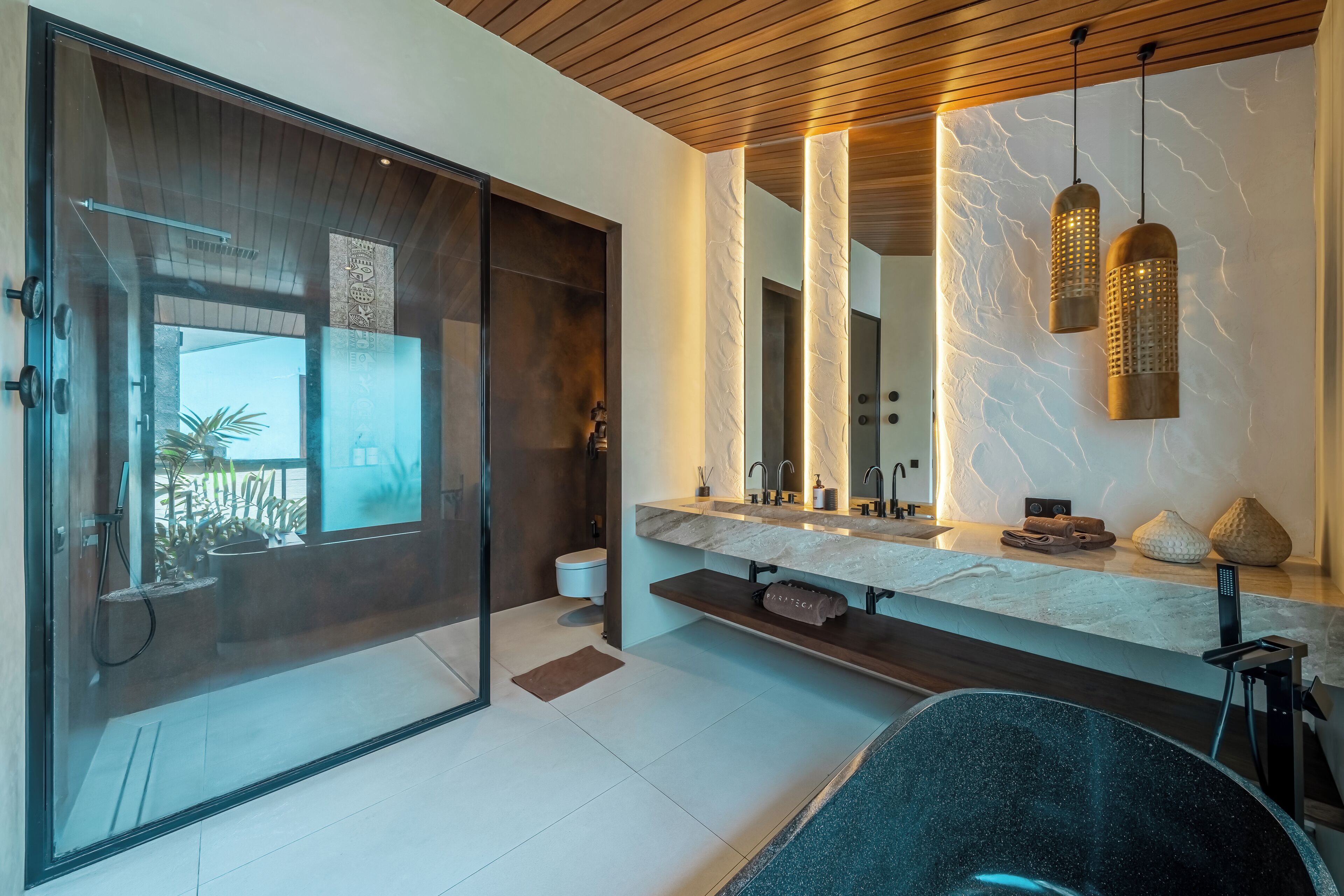 Un baño moderno con cabina de ducha de vidrio, un espejo grande y un lavabo empotrado con encimera de mármol.