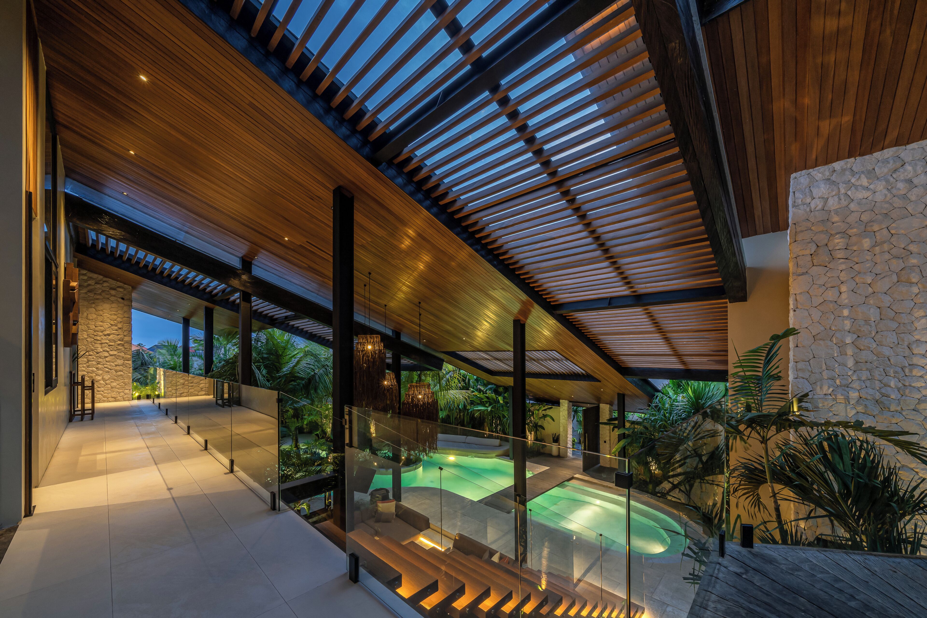 A modern architectural interior with a pool, glass railings, and natural light.