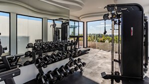 Ein Fitnessstudio mit Gewichthebern, großen Fenstern und Blick ins Freie.