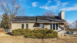 A single-story house with a dark roof, beige siding, and a chimney. - Newly remodeled 3-bedroom ranch with pool table, patio, and grill in Urbandale. (Urbandale)
