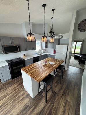 A modern kitchen with a central island, stainless steel appliances, and pendant lighting. - Newly remodeled 3-bedroom ranch with pool table, patio, and grill in Urbandale. (Urbandale)