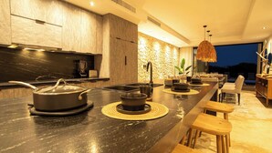 A modern kitchen with a long island, built-in appliances, and a dining area with wooden chairs.