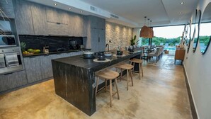 A modern kitchen with a large island, built-in appliances, and a dining area with a view. - Casa Serena: Oasis in front of the Caribbean with Pool and Terrace (Isla Mujeres)