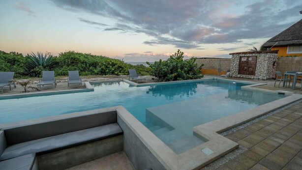Une piscine avec des chaises longues et un mur en pierre.