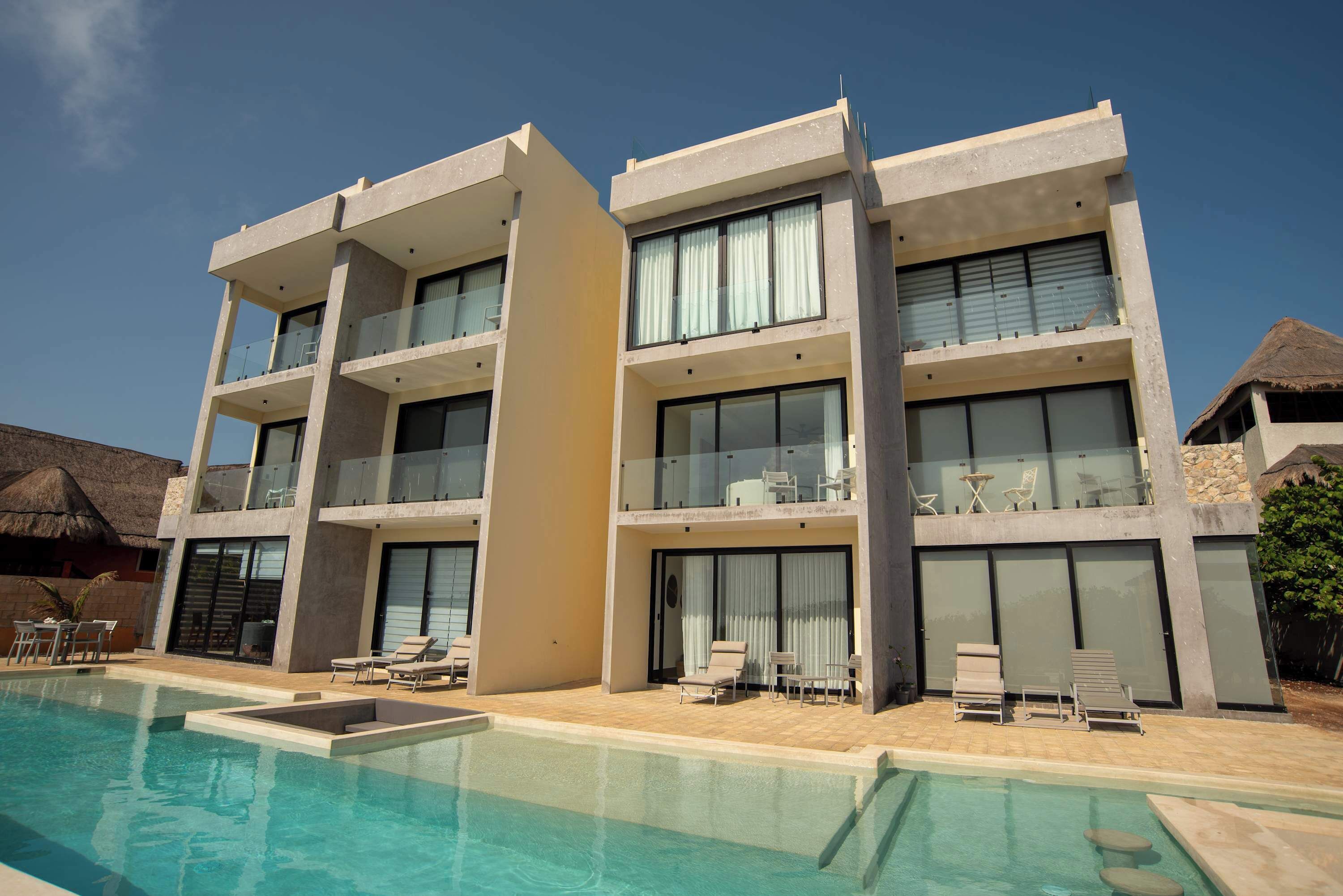Un hôtel moderne doté d’une piscine, de nombreux balcons et d’espaces extérieurs aménagés pour se détendre.