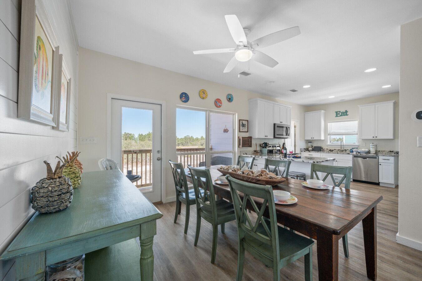 A dining area with a table and chairs, a ceiling fan, and a view of the outdoors.