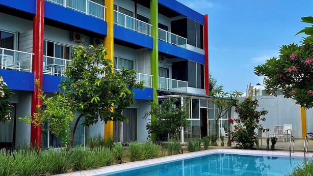 A multi-story building with balconies, a swimming pool, and surrounding greenery. - JEPARA BEACH HOTEL (Tahunan)