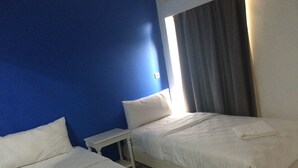 A hotel room with two beds, a nightstand, and a window with curtains. - JEPARA BEACH HOTEL (Tahunan)